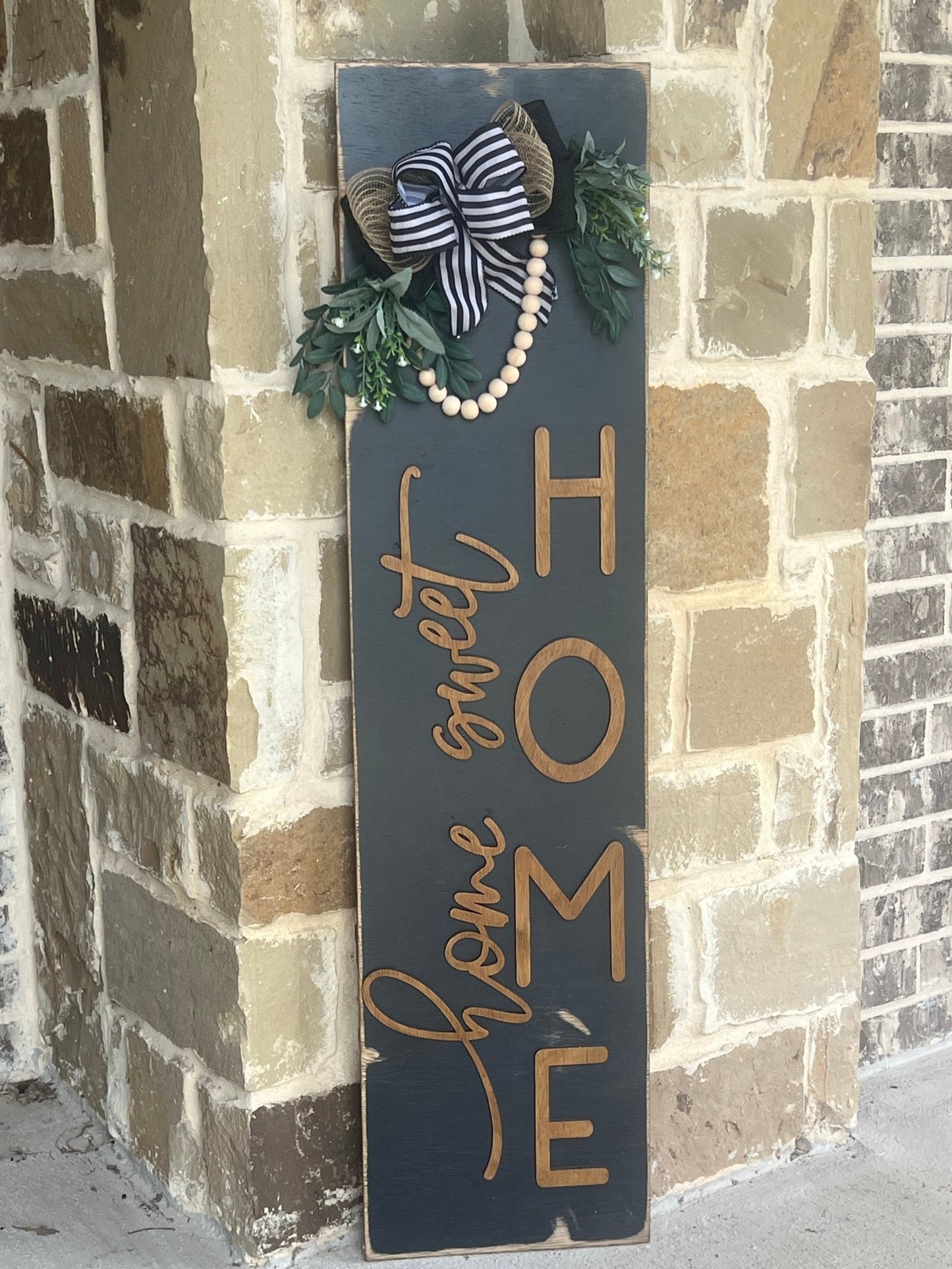 Rustic modern Black Wood Home Sweet Home door lean, 12x48 inches, perfect for cozy decor leaning on stone.