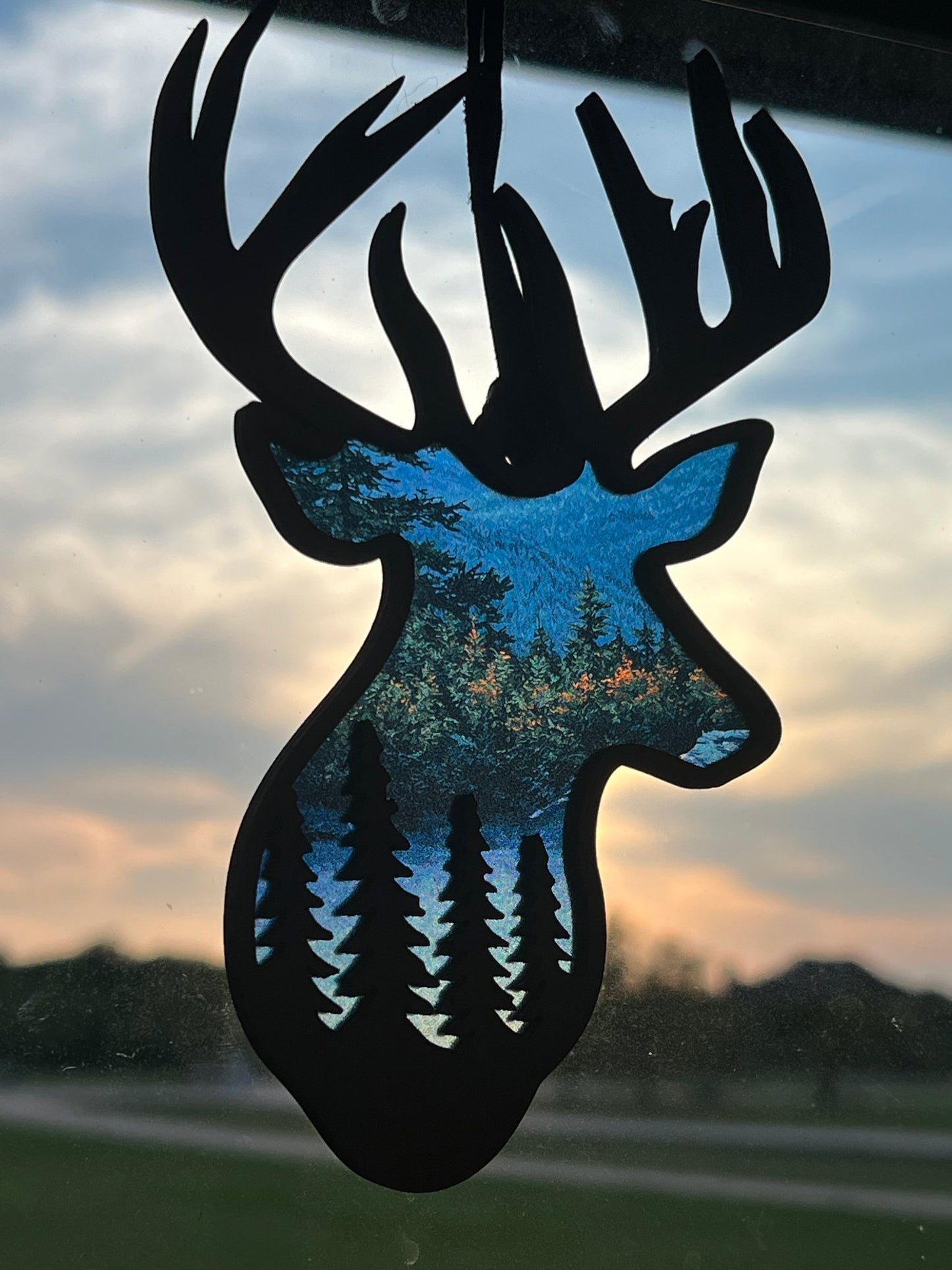 Handmade Buck Sky and Trees Suncatcher featuring natural wood and multicolor acrylic in sunlight.