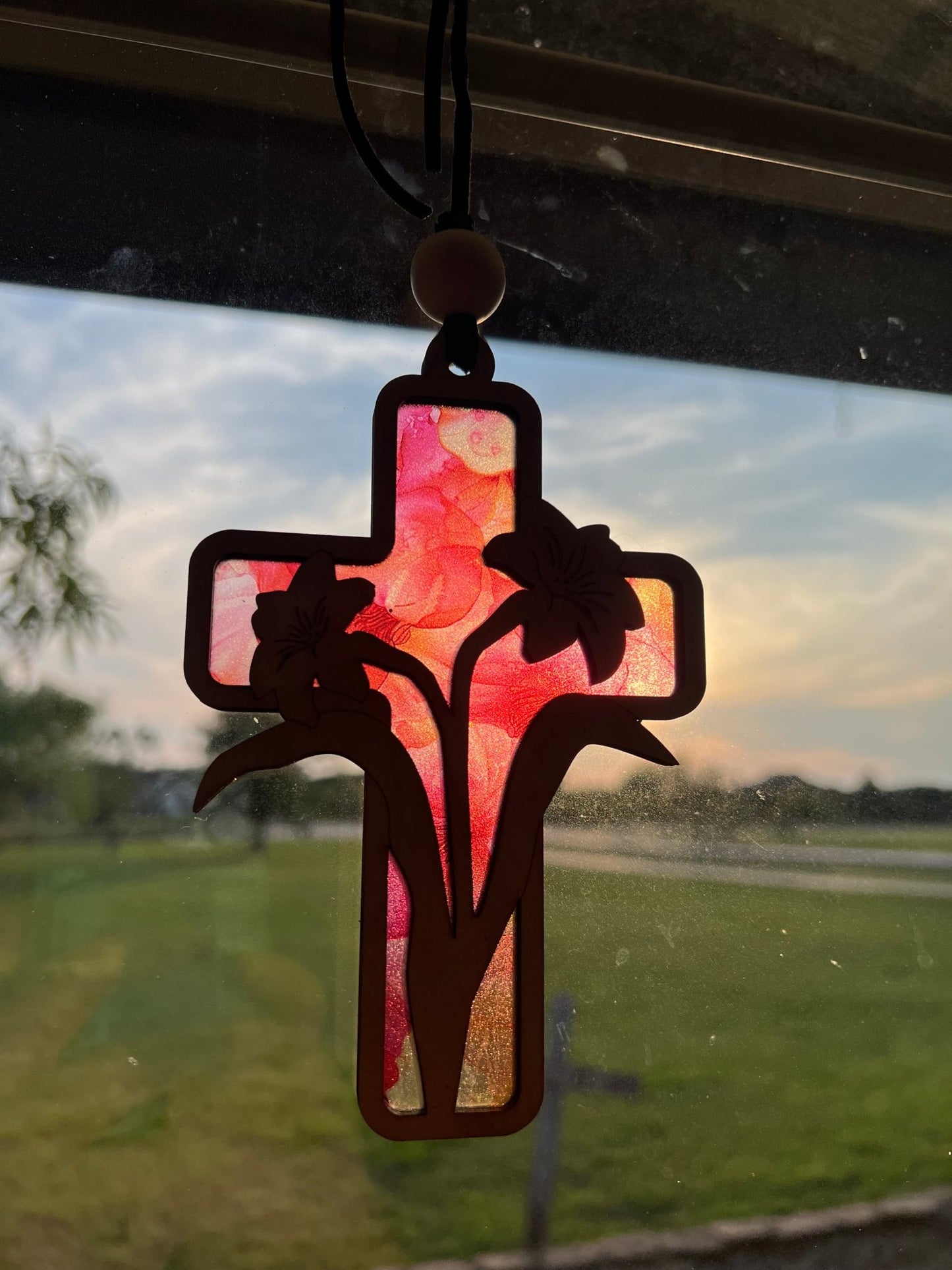 Lily Cross Suncatcher with a stained glass effect, crafted from colorful acrylic and wood in sunlight.