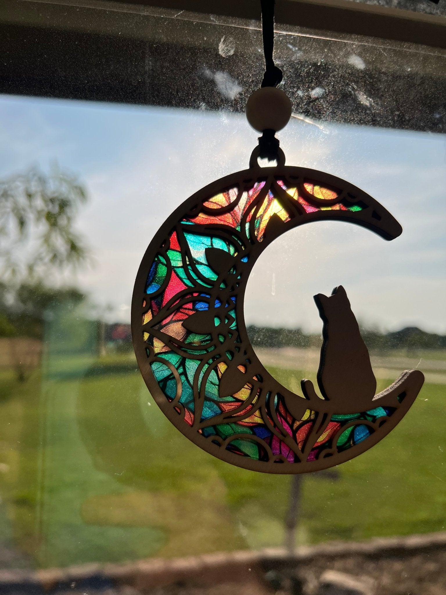 Rustic Cat on the Moon suncatcher with wood and acrylic, in natural hues in sunlight.