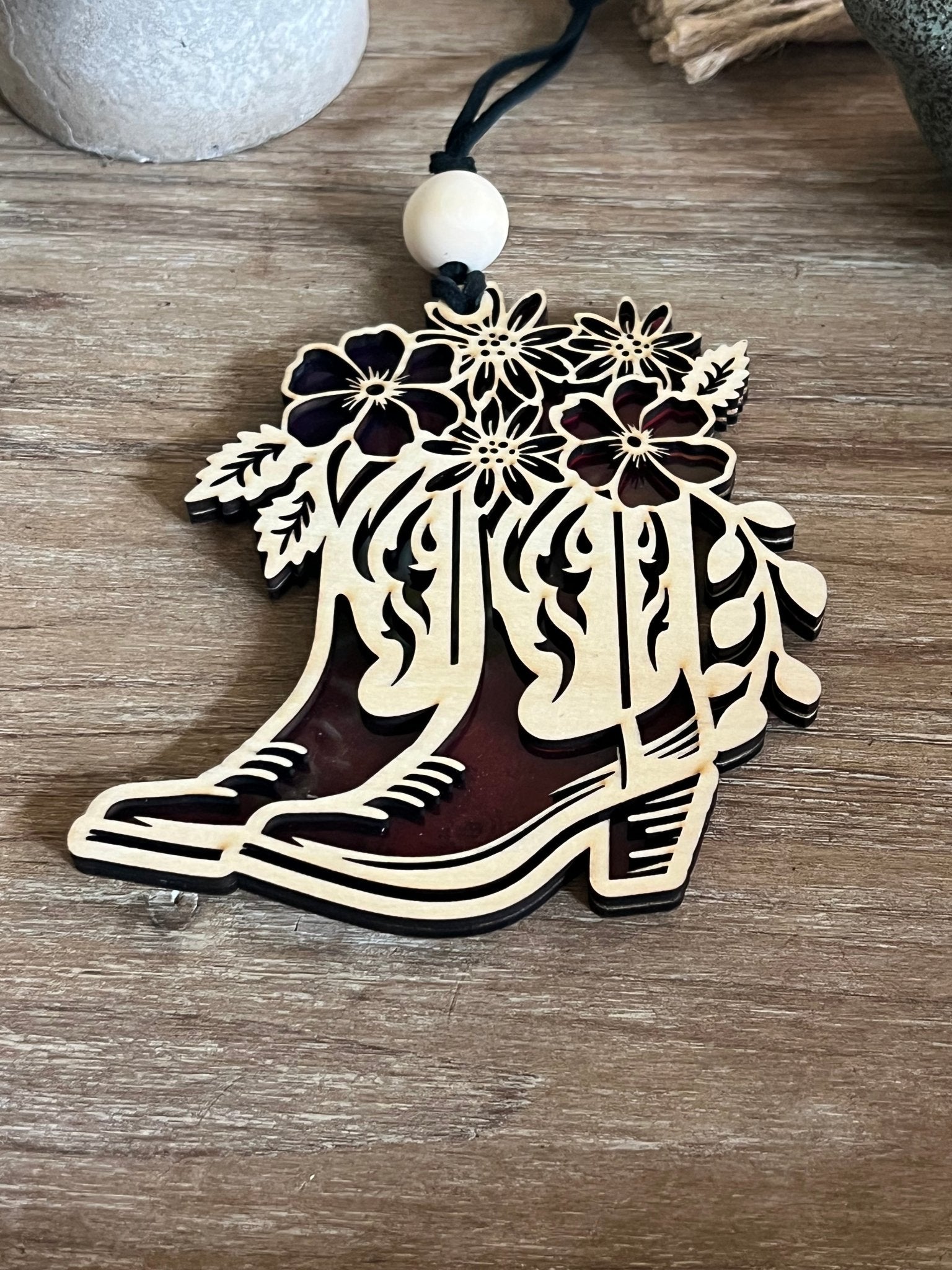 Rustic suncatcher featuring boots and flowers with stained glass effect, made of acrylic and wood in multicolor hues unlit.