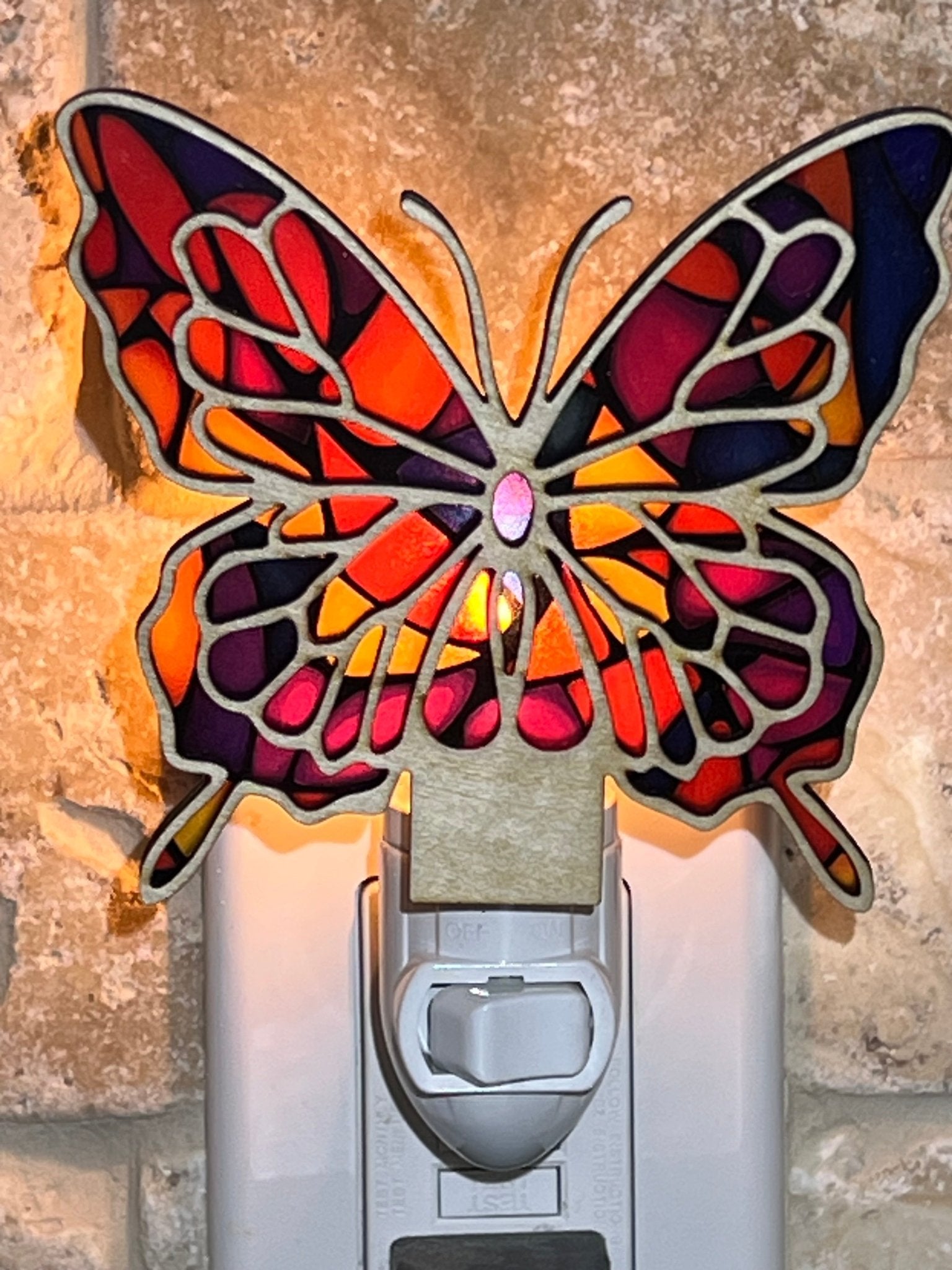 Colorful butterfly nightlight with stained glass effect on wood and acrylic lit in regular room.
