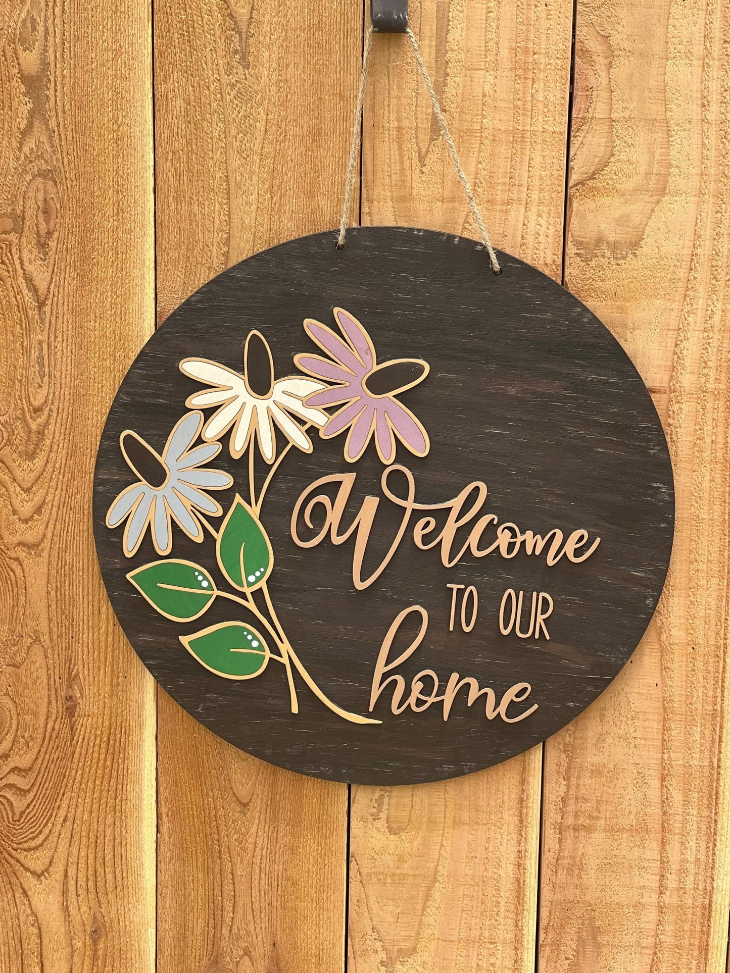 Rustic coneflower welcome door hanger made from walnut-stained wood with multicolor accents, on unpainted fence.
