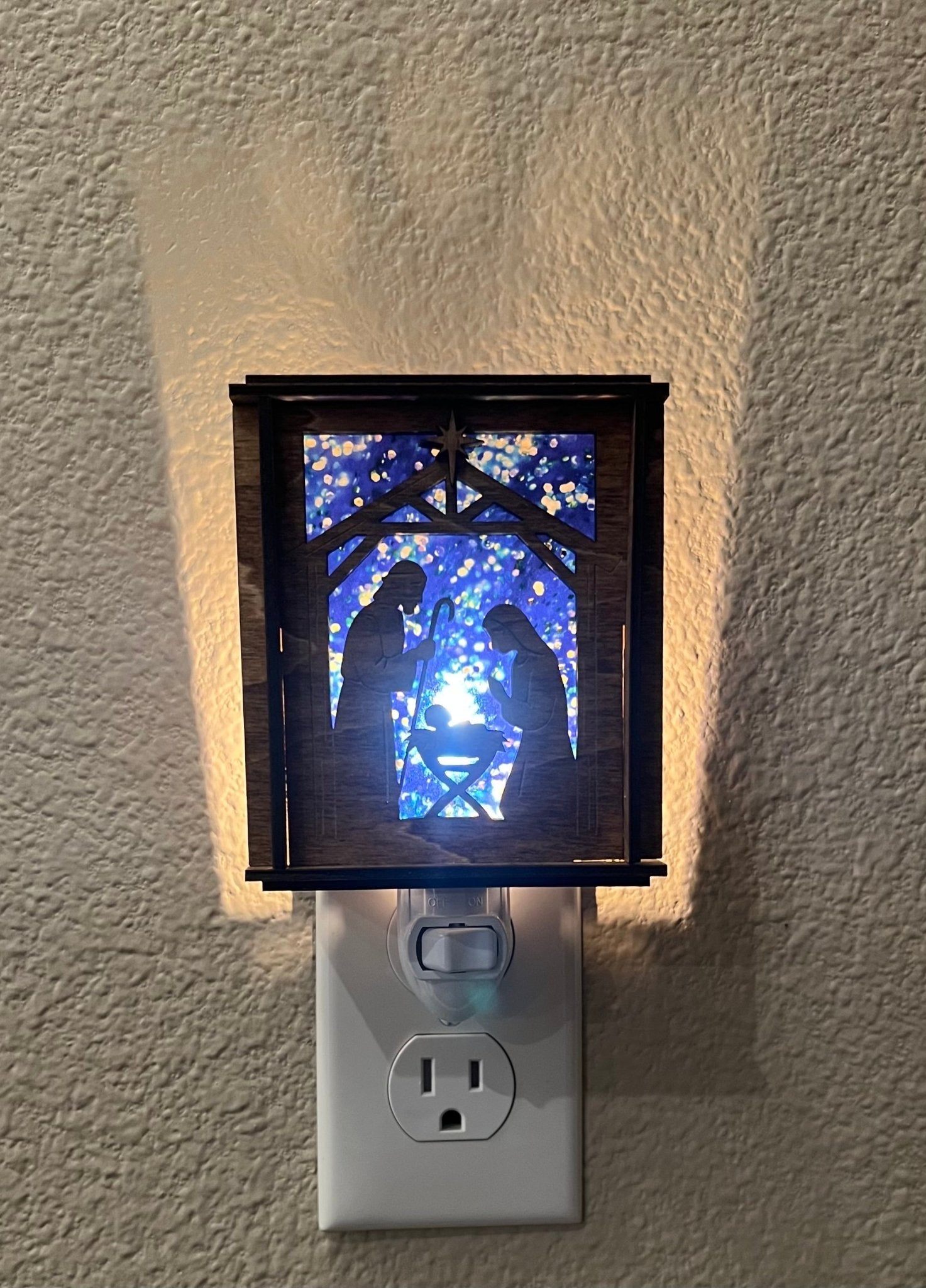 A Christmas Nativity Lantern Nightlight in golden oak with wood and acrylic materials lit front view.