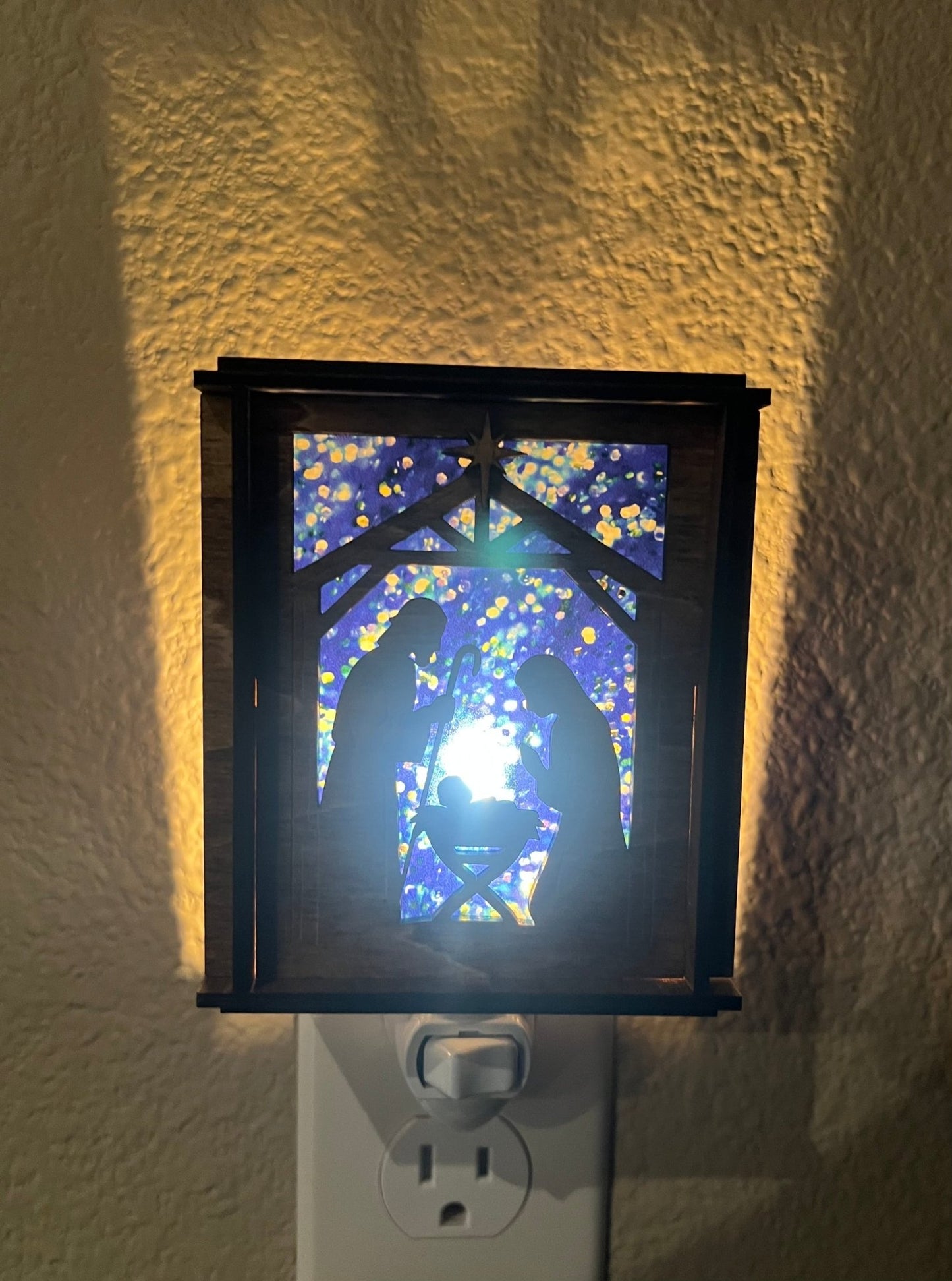 A Christmas Nativity Lantern Nightlight in golden oak with wood and acrylic materials - lit with front view.