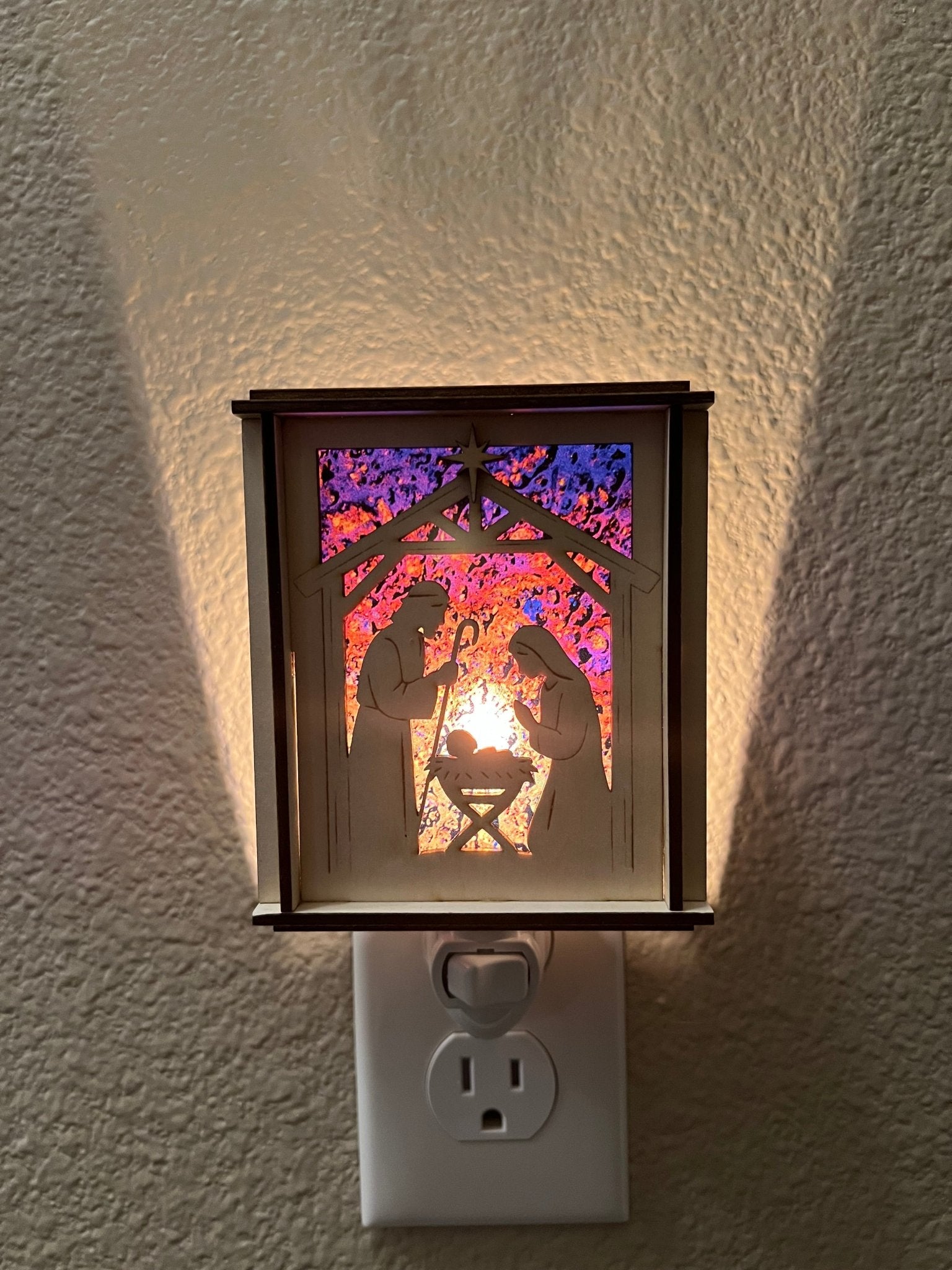 Natural wood Christmas Nativity Lantern Nightlight with multicolor designs in hall and lit with front view.