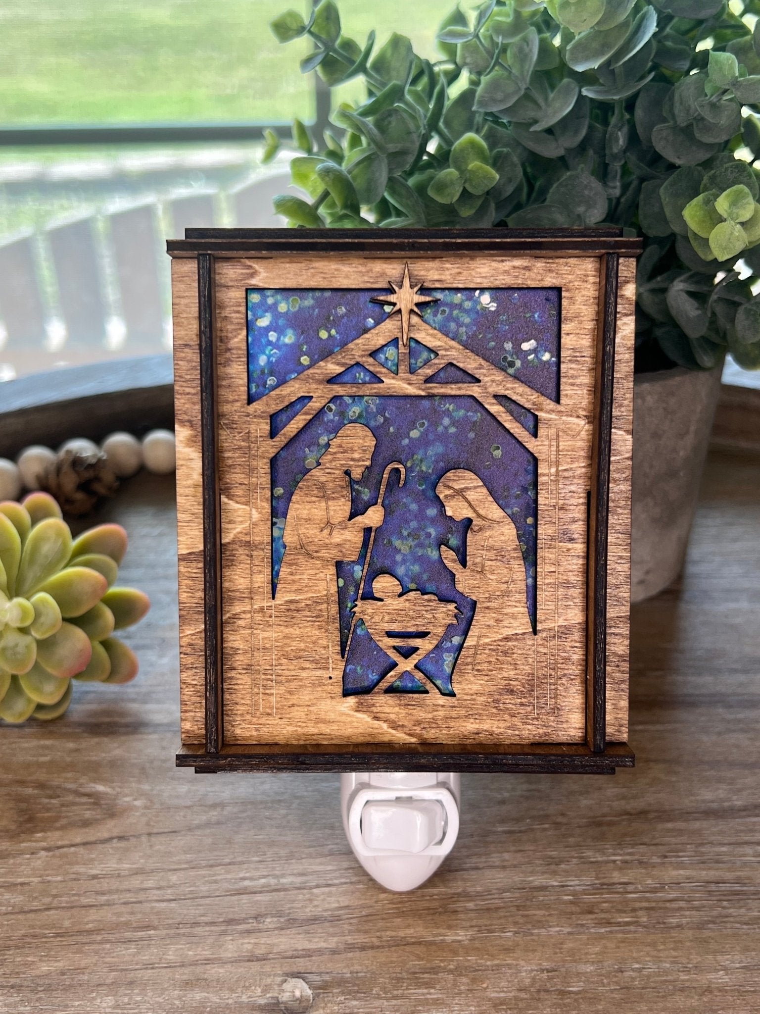 A Christmas Nativity Lantern Nightlight in golden oak with wood and acrylic materials - unlit on tray.