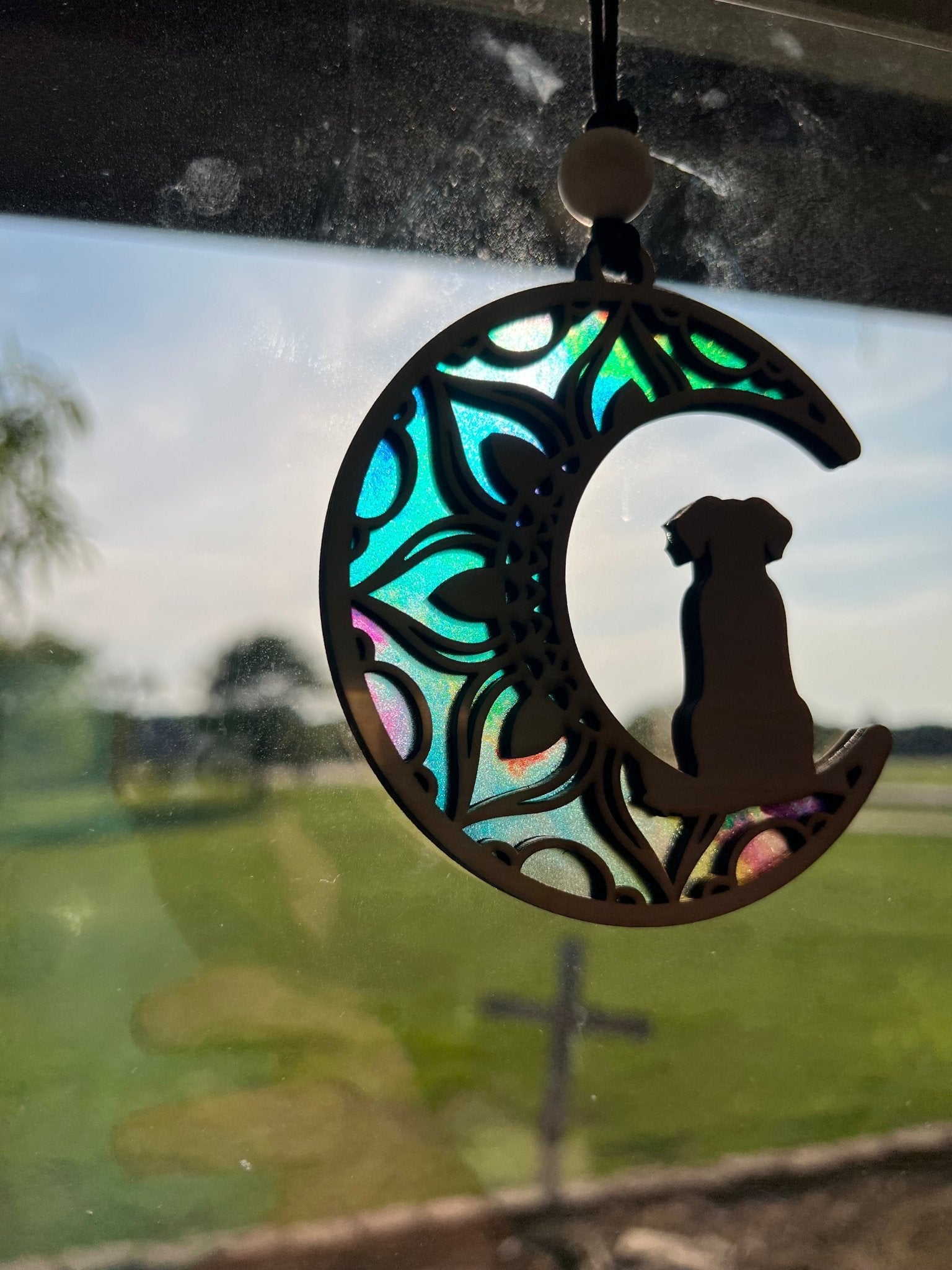 Dog on the Moon suncatcher with stained glass effect, made of wood and acrylic in sunlight.
