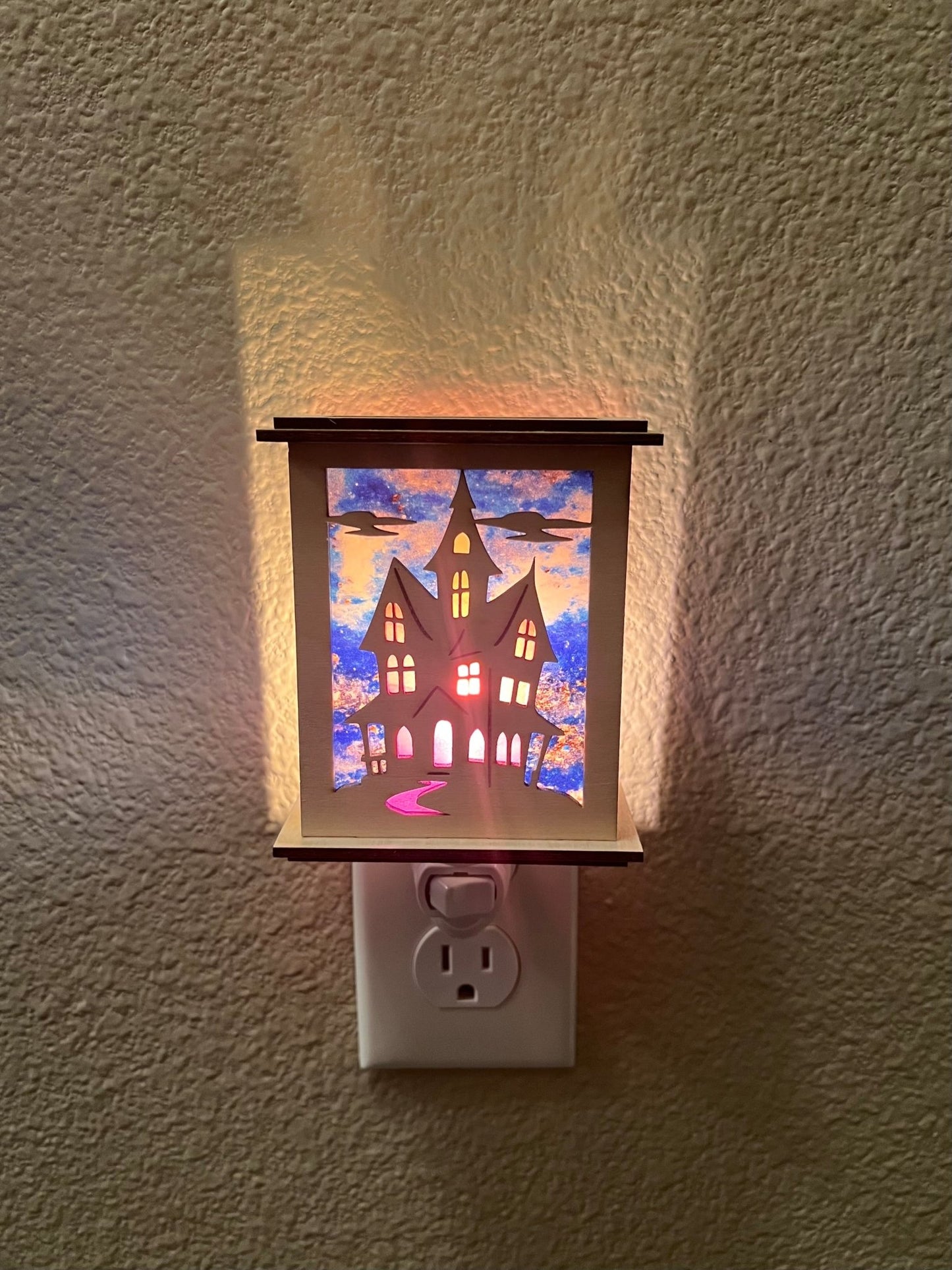 Halloween Haunted House Lantern Nightlight made from wood and acrylic, showcasing rustic charm and multicolor glow lighted in a lit hallway with front view.
