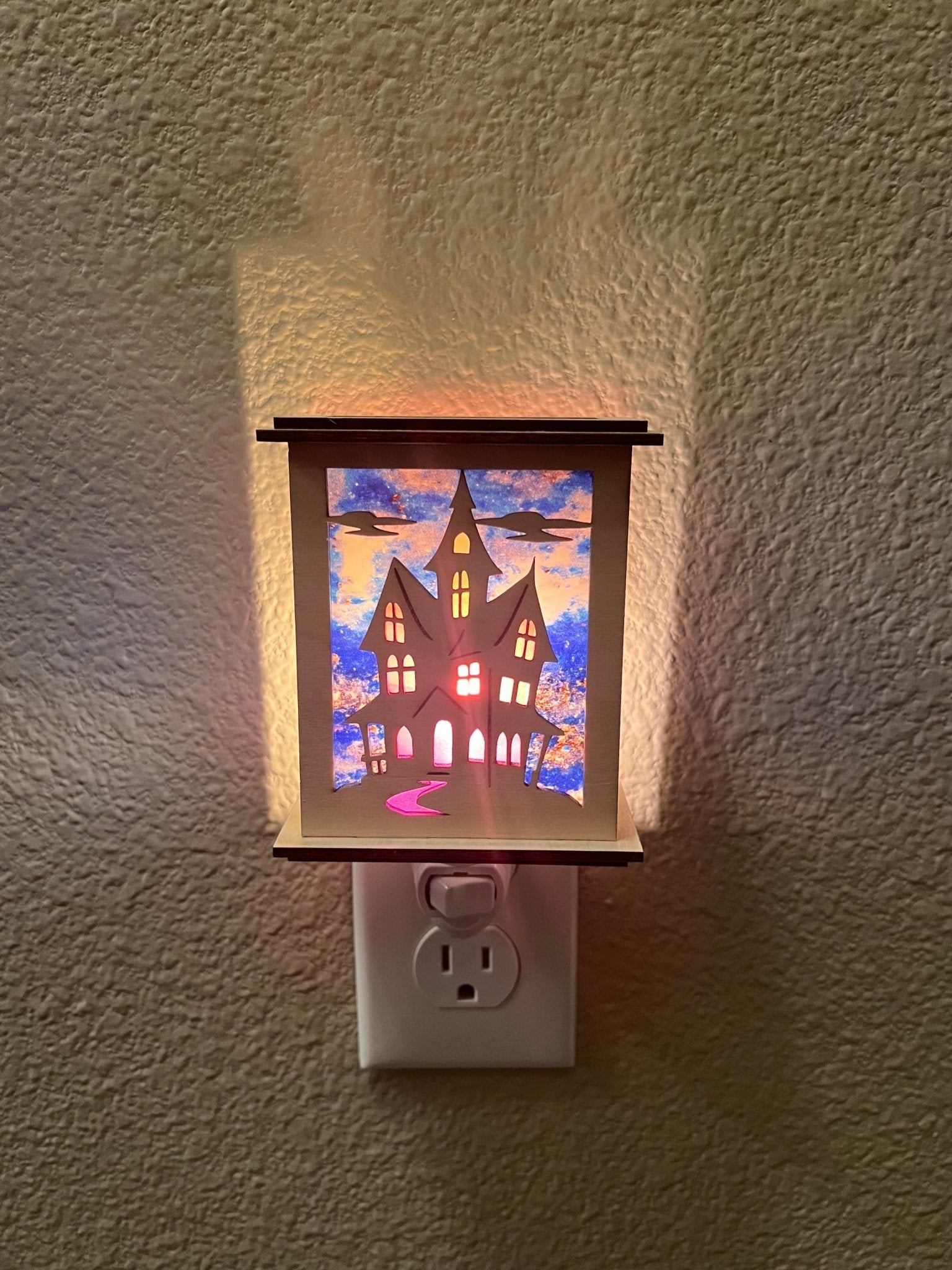 Halloween Haunted House Lantern Nightlight made from wood and acrylic, showcasing rustic charm and multicolor glow lighted in a lit hallway with front view.
