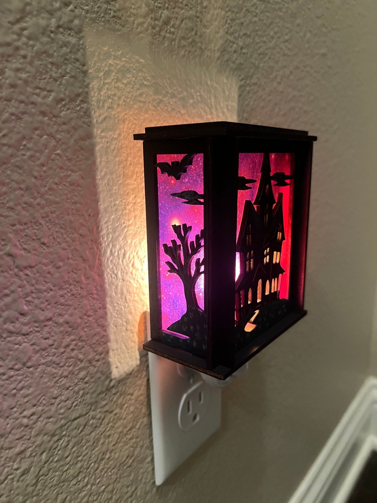 A haunted house hand painted stained glass effect nightlight, multicolor acrylic and black wood design - lit left side view.