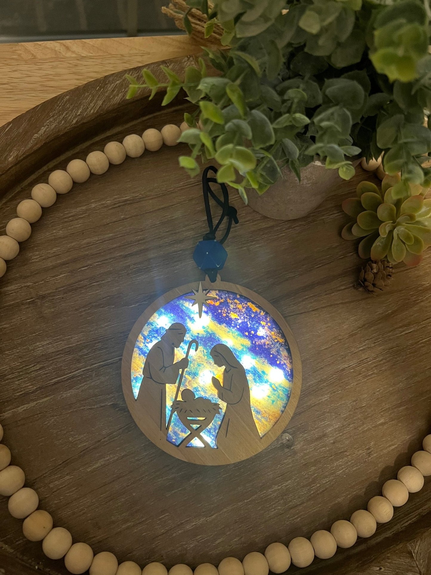 Lighted Christmas Nativity Ornament made of wood and acrylic, featuring a rustic, multicolor design lighted and zoomed in.
