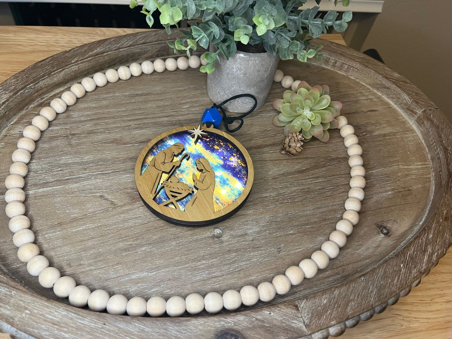 Lighted Christmas Nativity Ornament made of wood and acrylic, featuring a rustic, multicolor design lit.