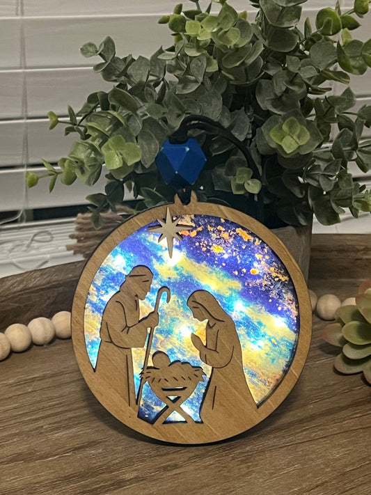Lighted Christmas Nativity Ornament made of wood and acrylic, featuring a rustic, multicolor design lighted and facing out.