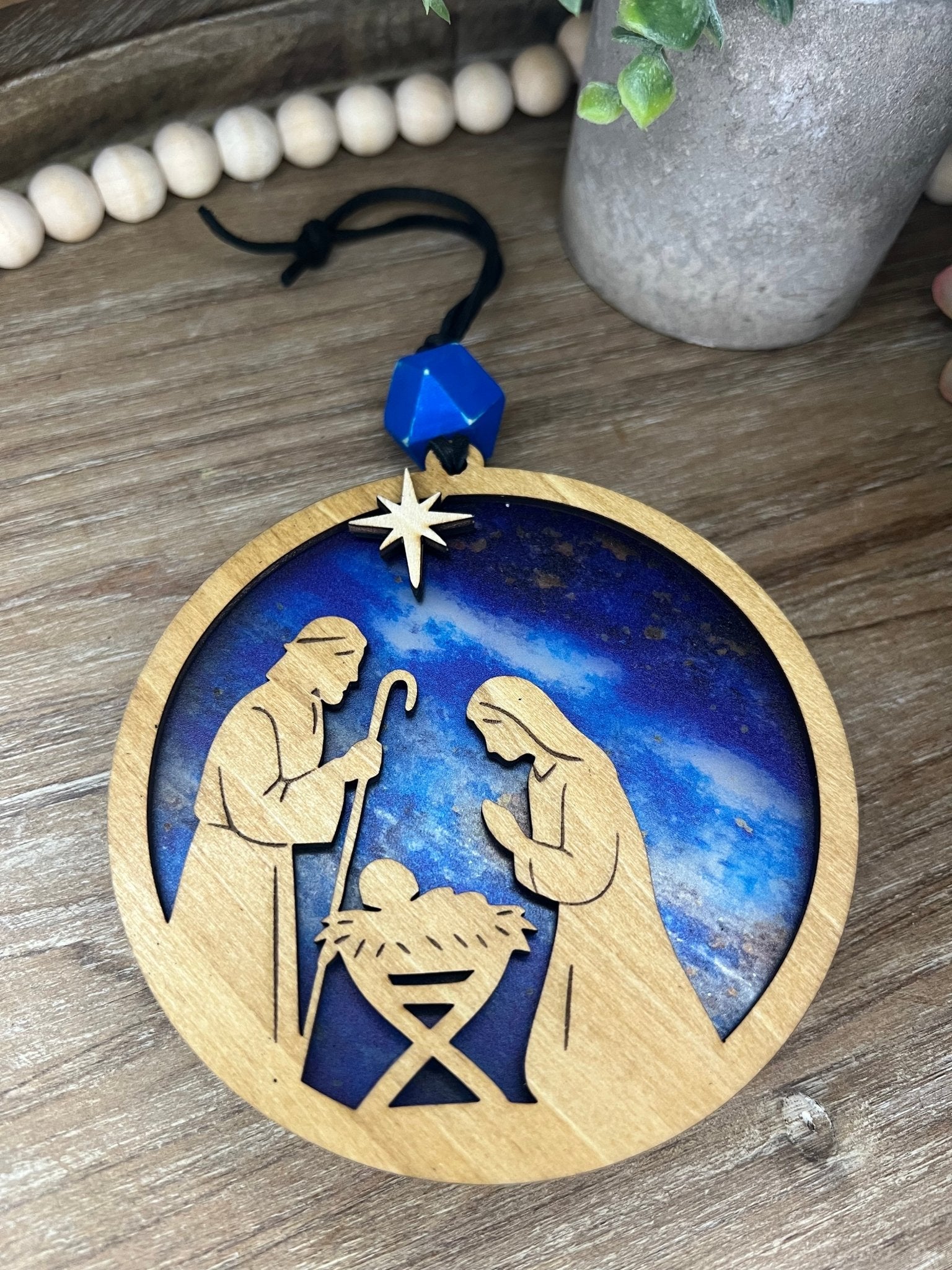 Lighted Christmas Nativity Ornament made of wood and acrylic, featuring a rustic, multicolor design unlit in natural light.