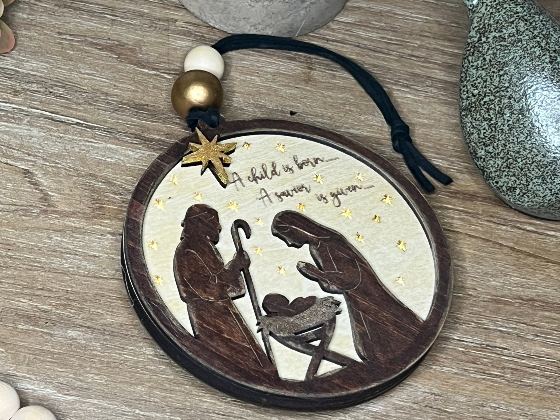 Lighted Christmas Nativity Ornament in natural wood with walnut stain lying on a tray.