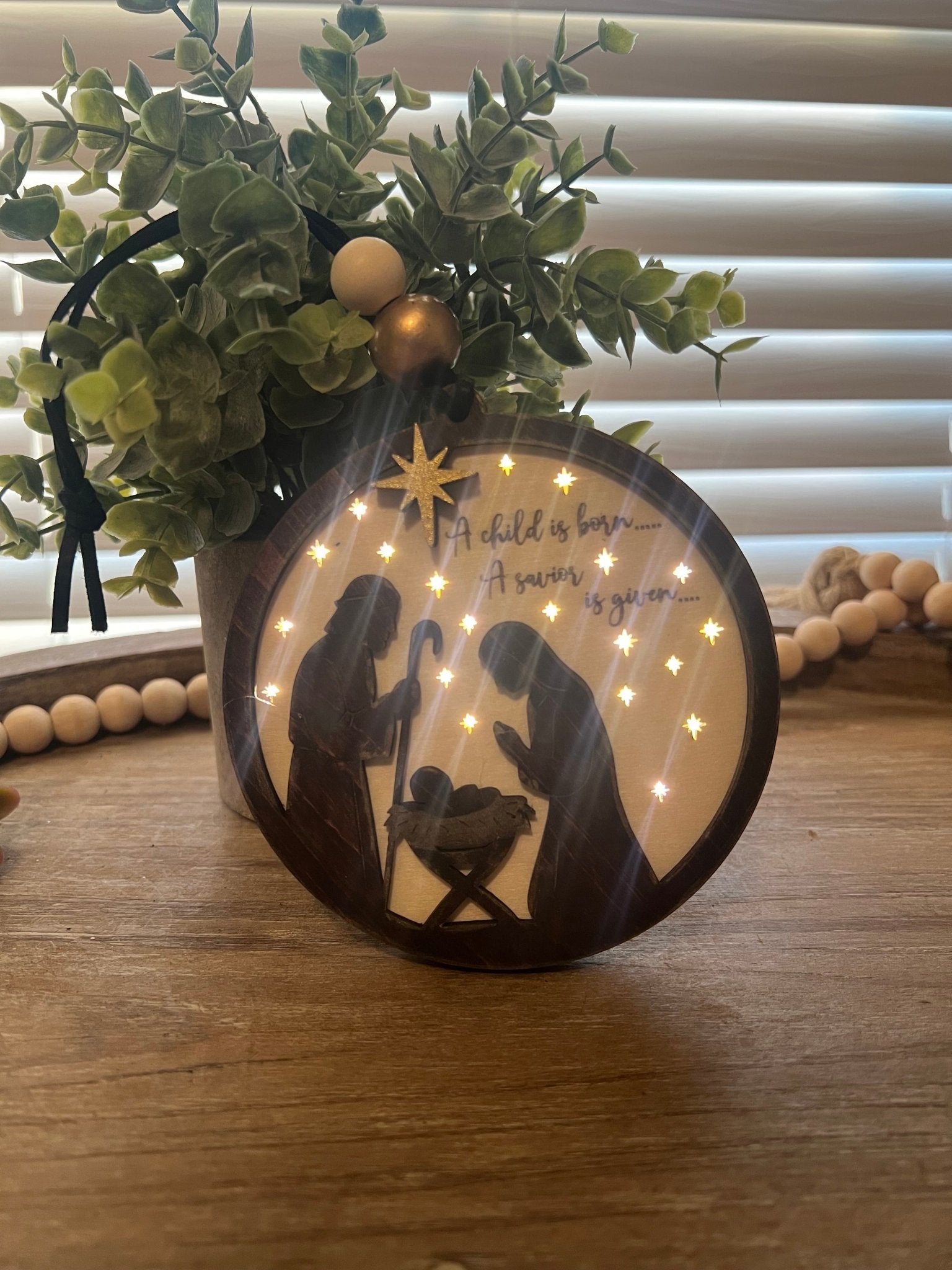 Lighted Christmas Nativity Ornament in natural wood with walnut stain loit in a darkend room.