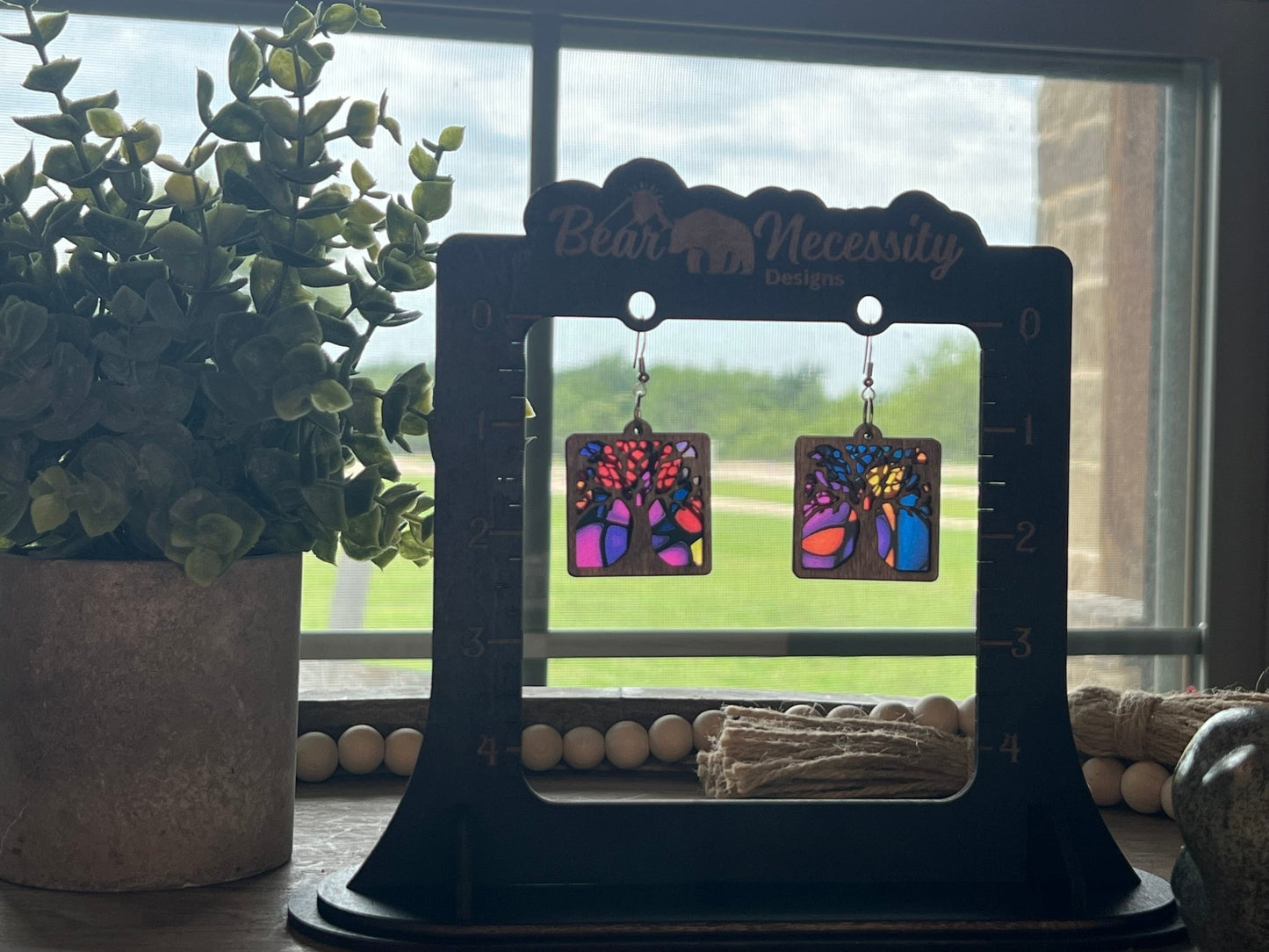 Multicolor Tree of Life earrings with a stained glass effect in wood and acrylic in sunlight.
