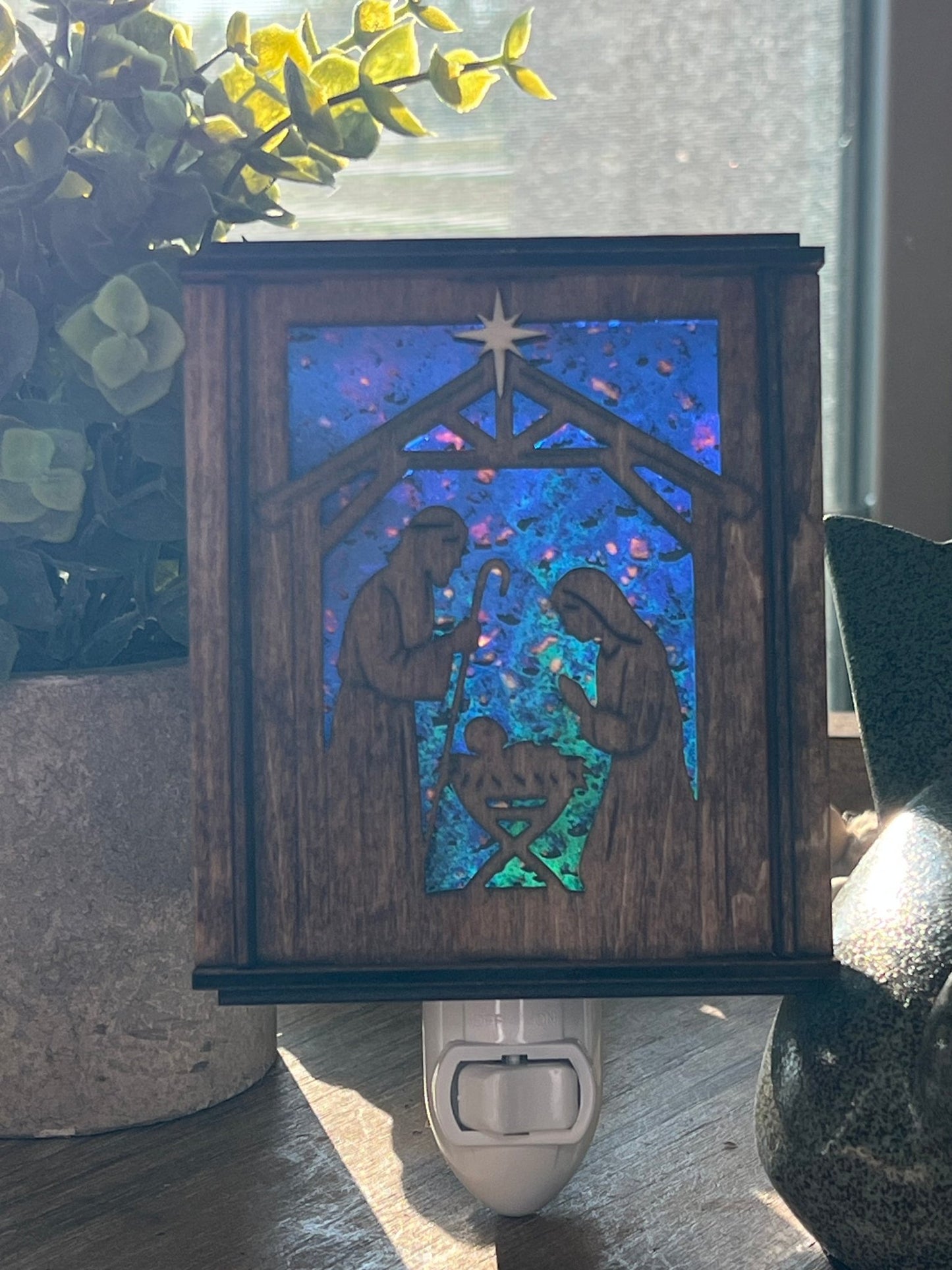 Golden oak stained wooden and acrylic nativity nightlight with rustic charm front view standing up wth sunilight shing through.