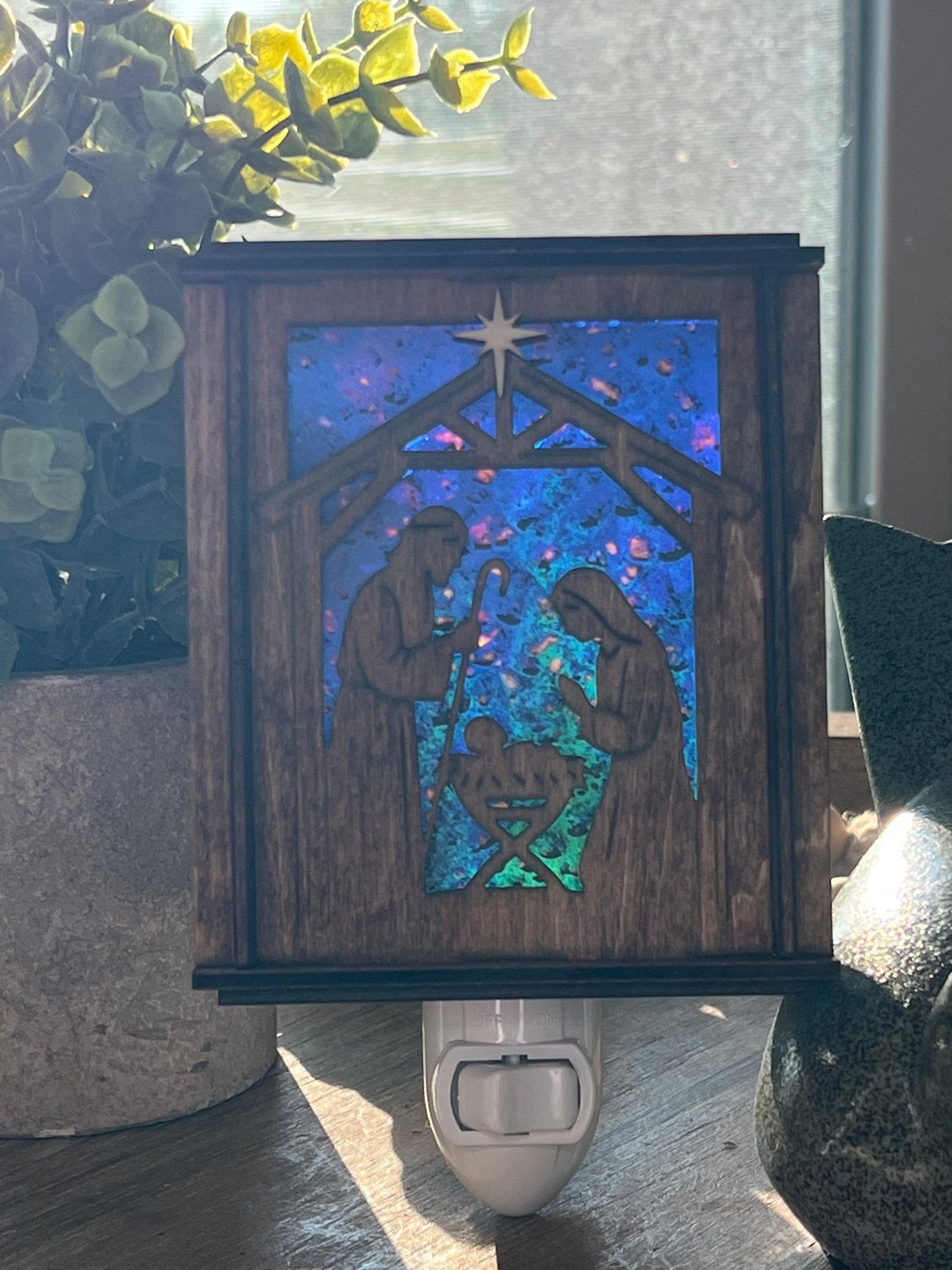 Golden oak stained wooden and acrylic nativity nightlight with rustic charm front view standing up wth sunilight shing through.