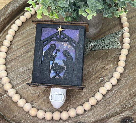 Rustic nativity nightlight lantern made of black wood and golden oak stained acrylic lynig down  with front view and unlit.