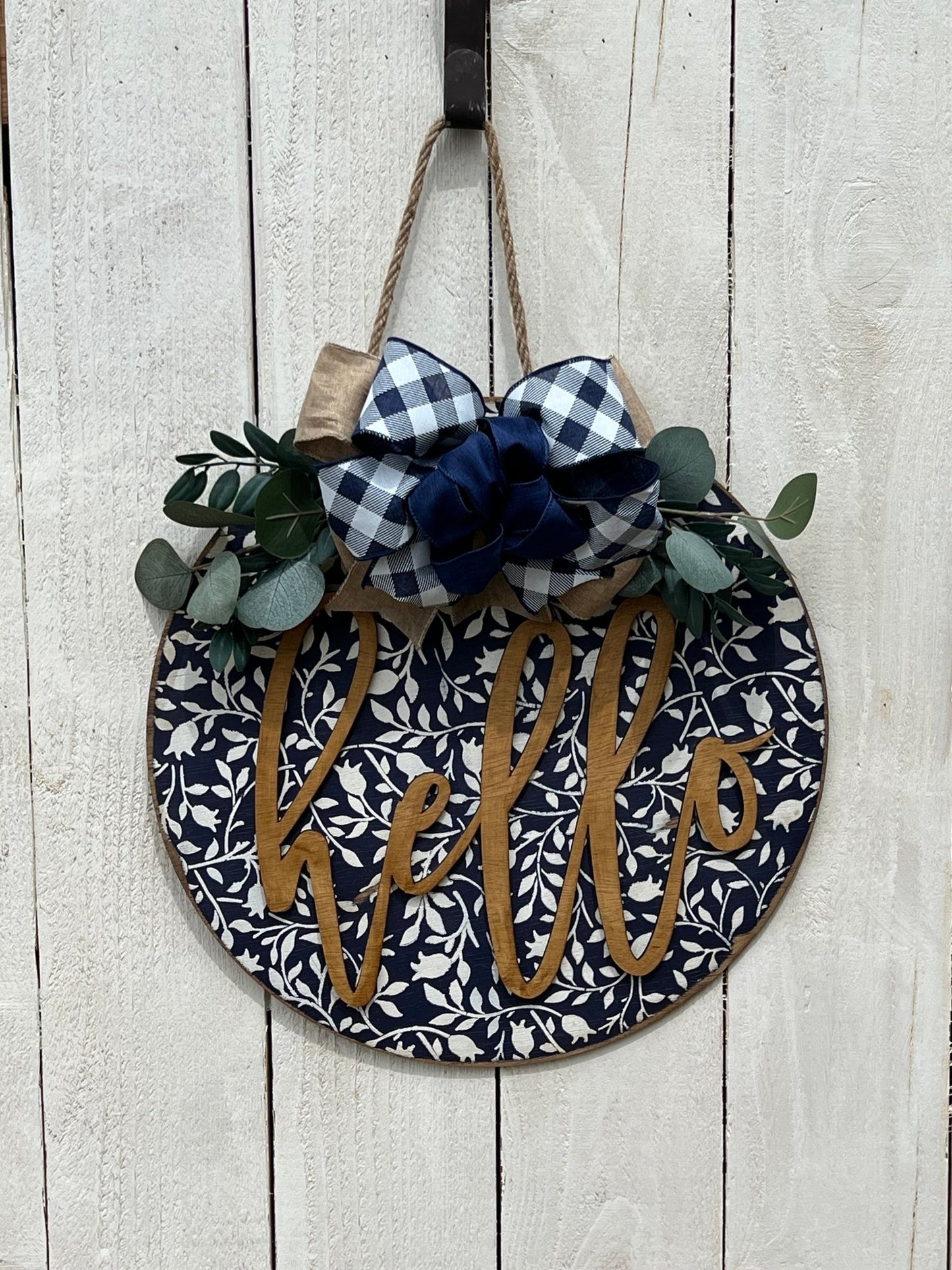 Navy wood hello door hanger with mini flowers on white door, perfect for rustic entryway decor.