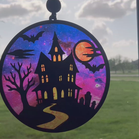 Hand painted suncatcher with a haunted house design on wood and acrylic, in vibrant colors in sunlight video.