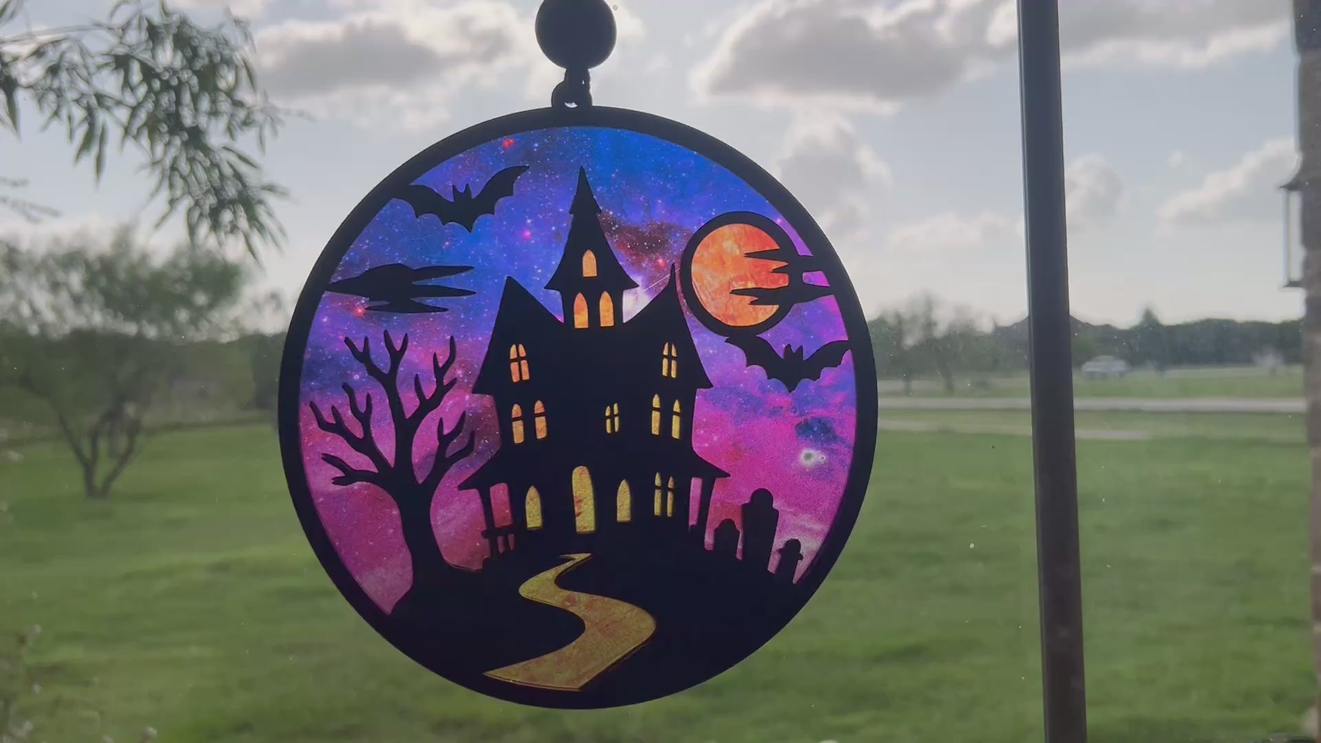Hand painted suncatcher with a haunted house design on wood and acrylic, in vibrant colors in sunlight video.