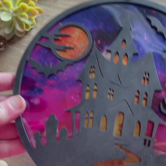 Hand painted suncatcher with a haunted house design on wood and acrylic, in vibrant colors - unlit back view video.