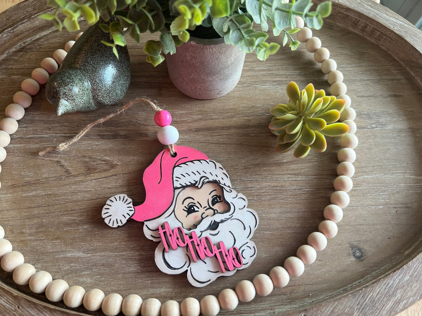 Handmade vintage Santa Christmas ornament with a pink hat, crafted from natural wood in natural light.
