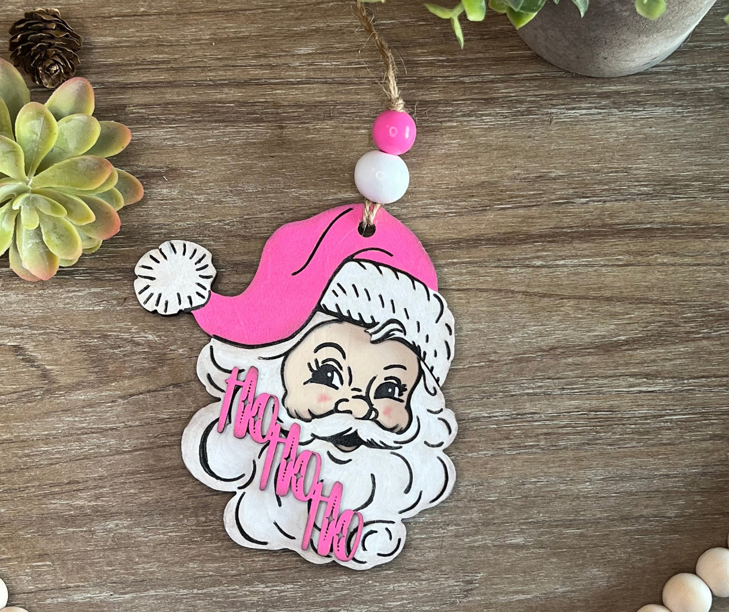 Handmade vintage Santa Christmas ornament with a pink hat, crafted from natural wood zoomed in.